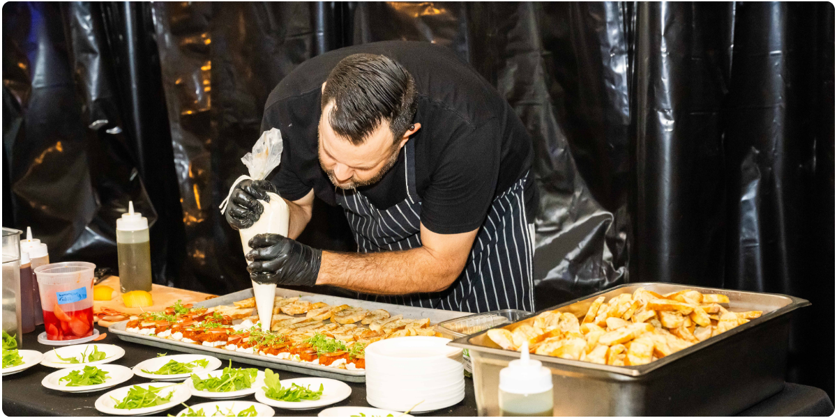 chef leaned over table, piping cheese onto crusts of bread